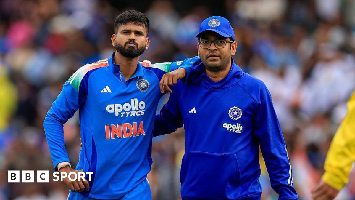 Shreyas Iyer (left) is helped from the field by a member of India's medical staff