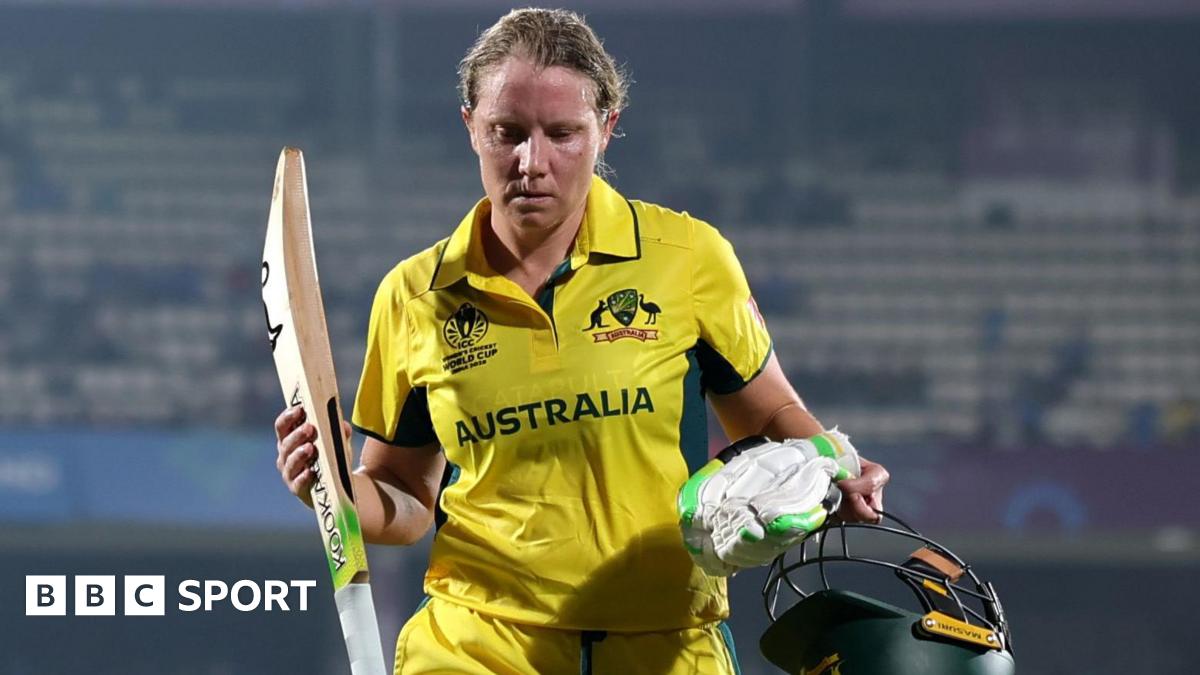 Alyssa Healy walks off the pitch holding her bat, helmet and gloves