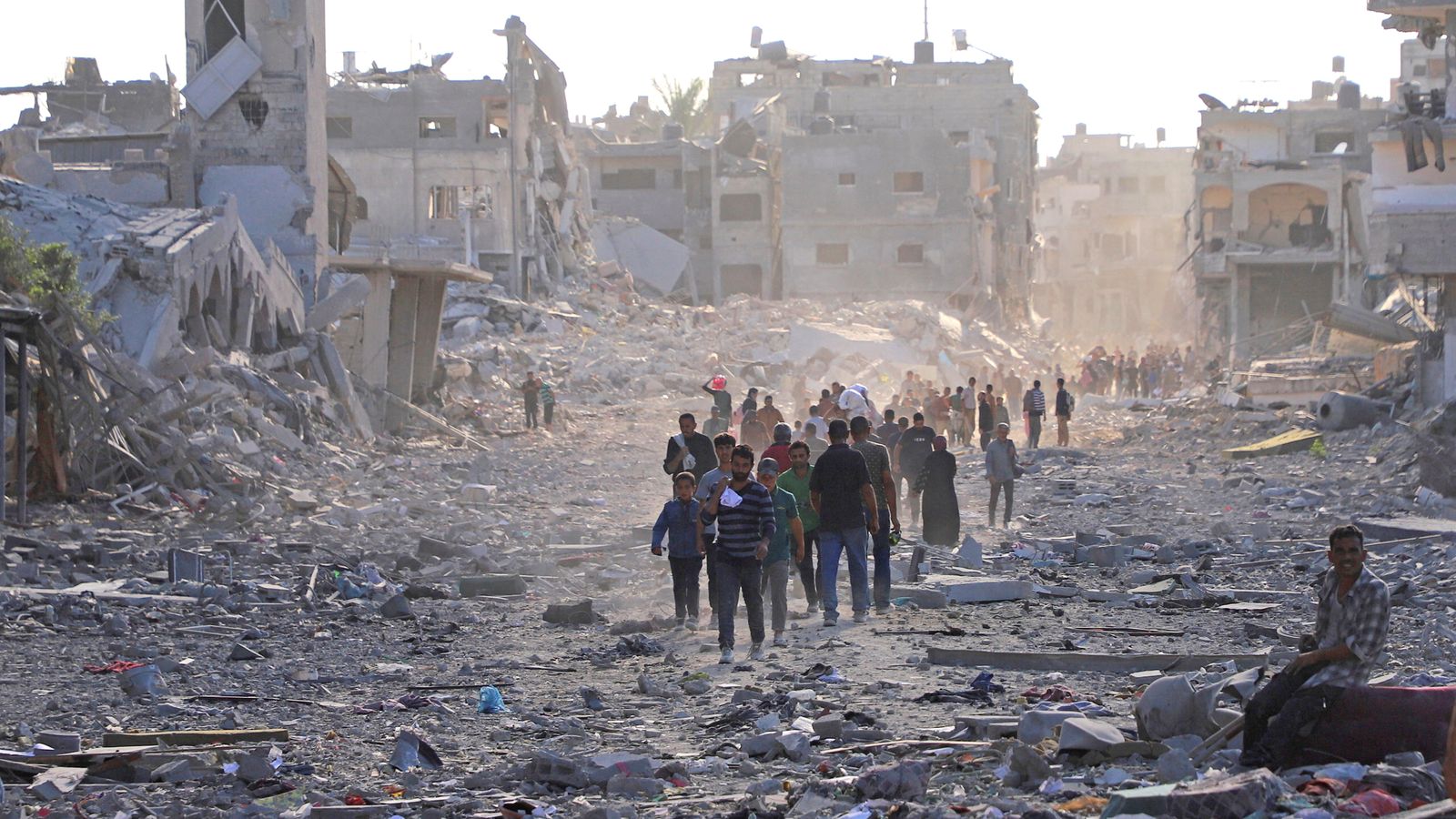 Palestinians walk through a damaged Gaza neighbourhood on Friday after Israel's government ratified a ceasefire with Hamas. Pic: Reuters