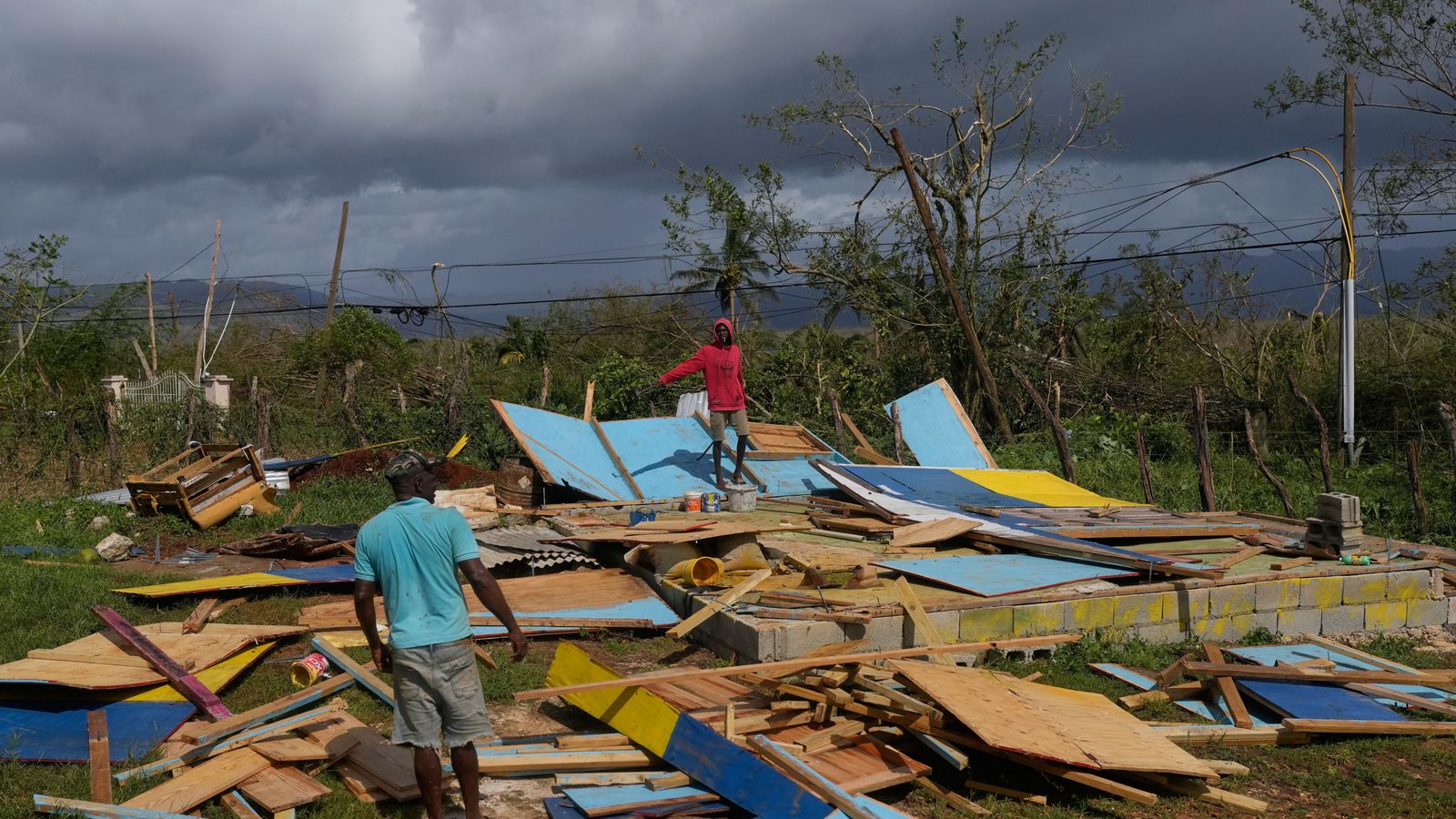 Residents stand on the wreckage of a house destroyed by Hurricane Melissa in Santa Cruz, Jamaica. Pic: AP