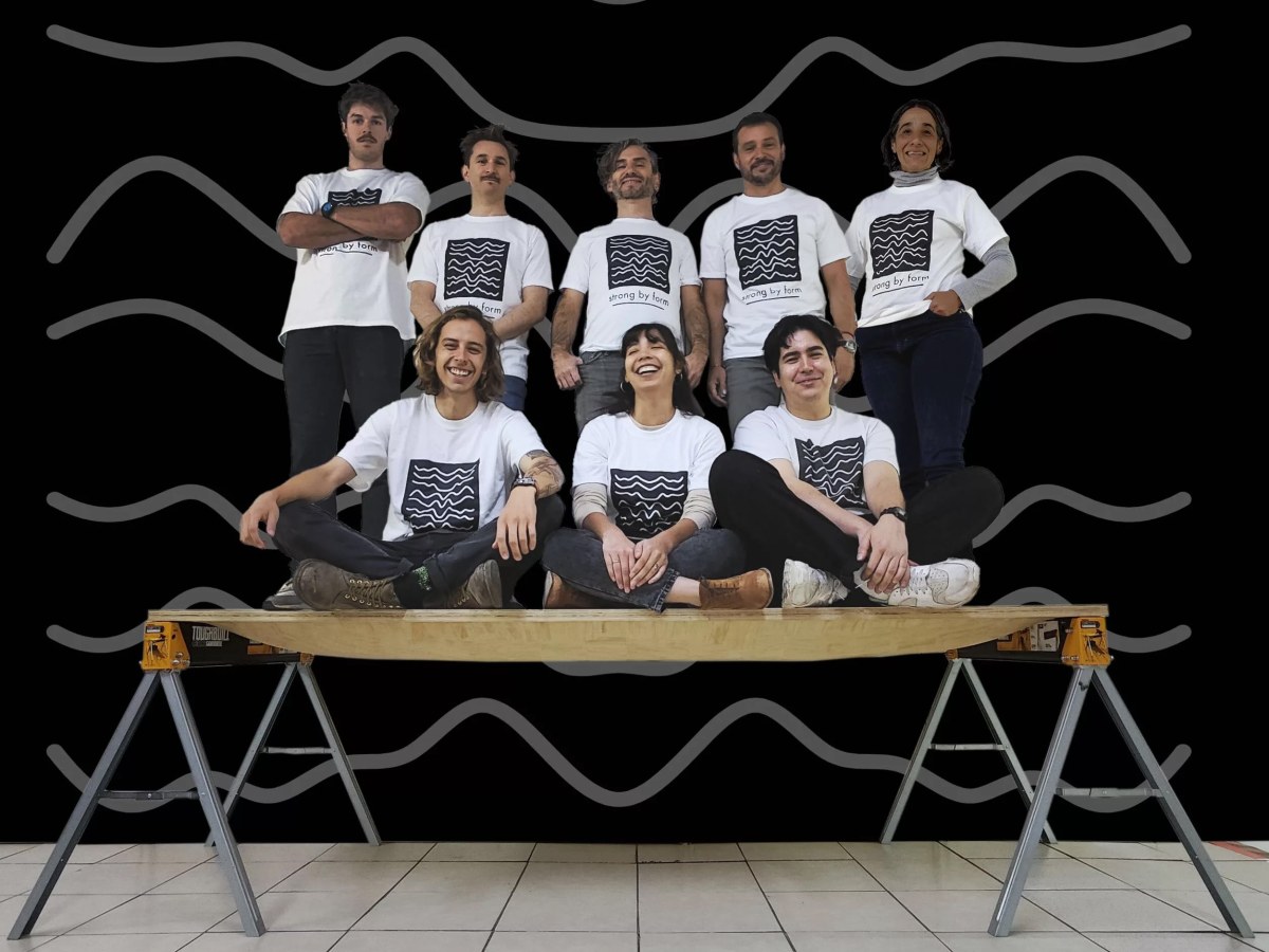 Eight people stand and sit on a thin panel of wood to demonstrate its strength.