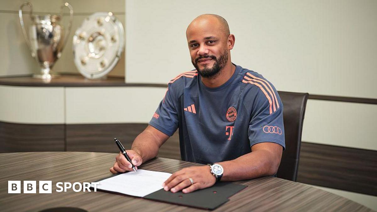 Vincent Kompany sits at a table and signs a piece of paper