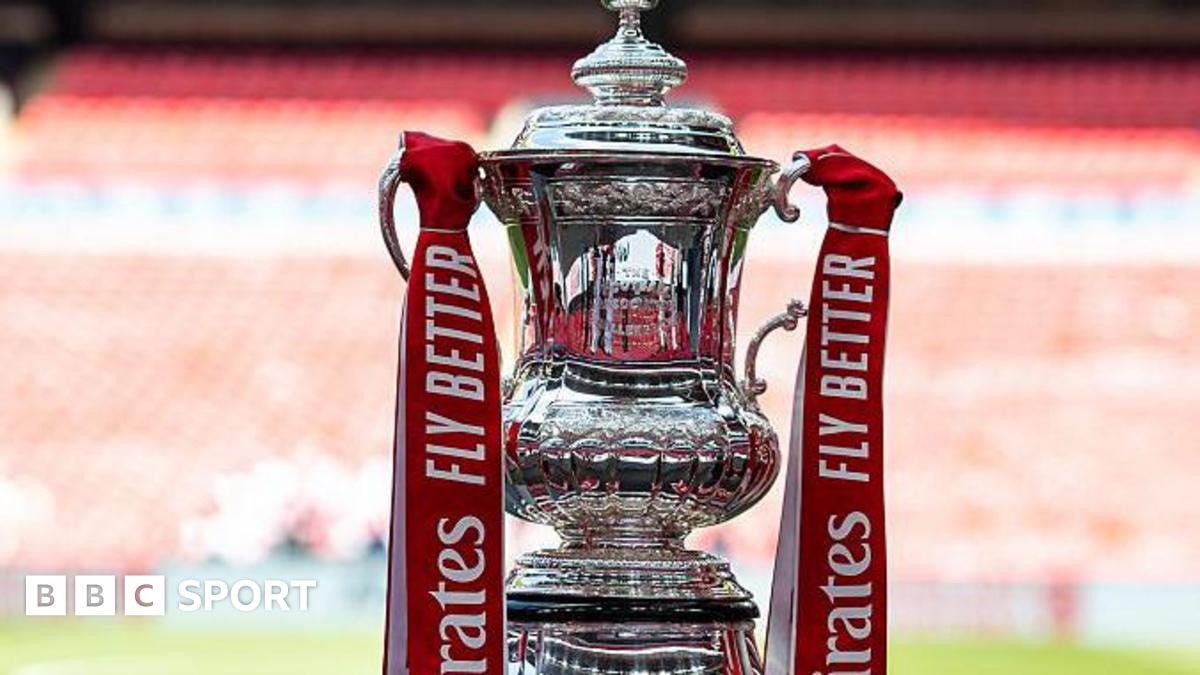 The FA Cup trophy, with red ribbons containing the sponsor's name, at Wembley