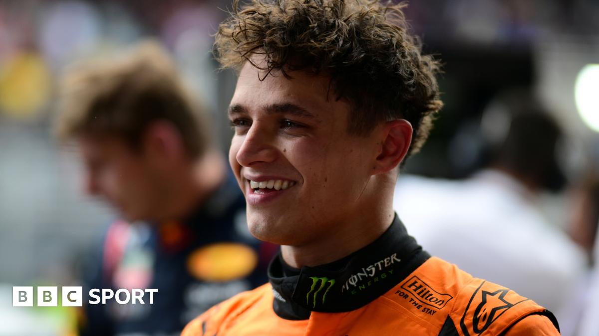 Lando Norris smiling after winning the Sao Paulo Grand Prix, with Max Verstappen visible in the background