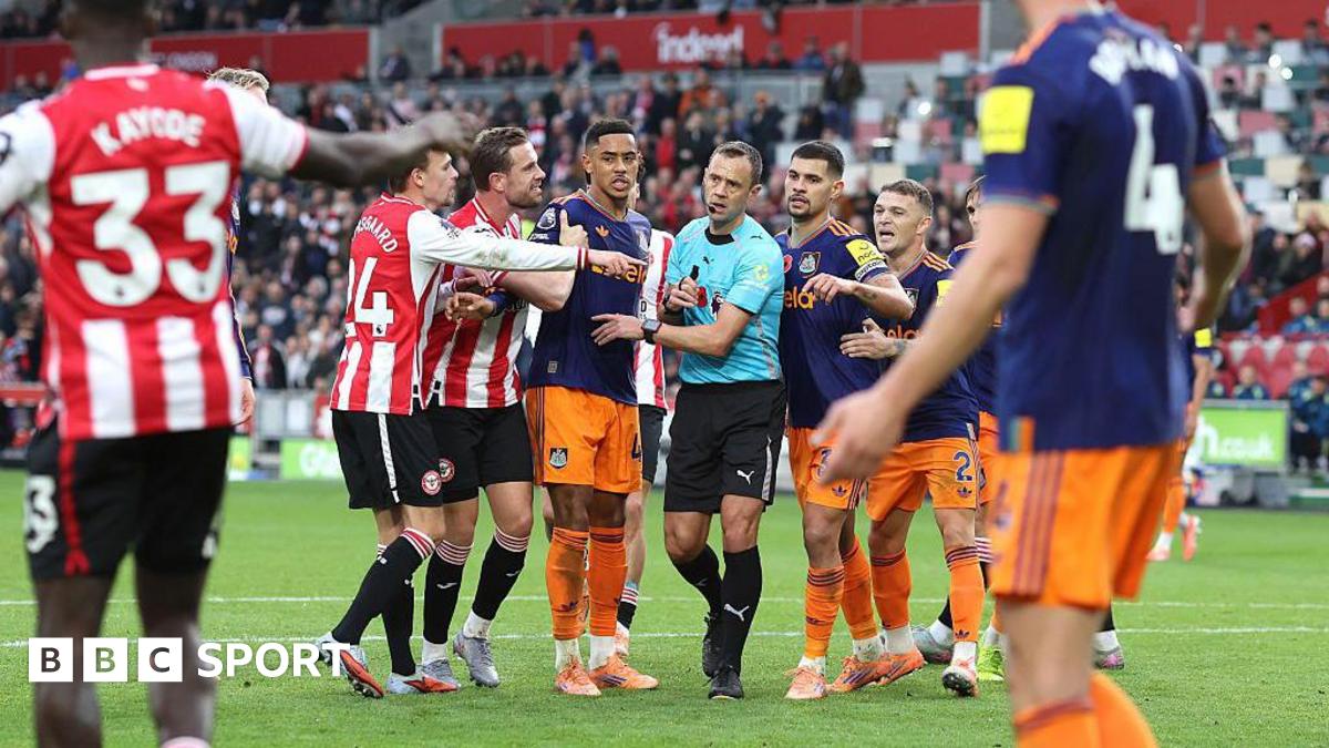 Players surround referee Stuart Attwell as he shows a yellow card to Dango Ouattara
